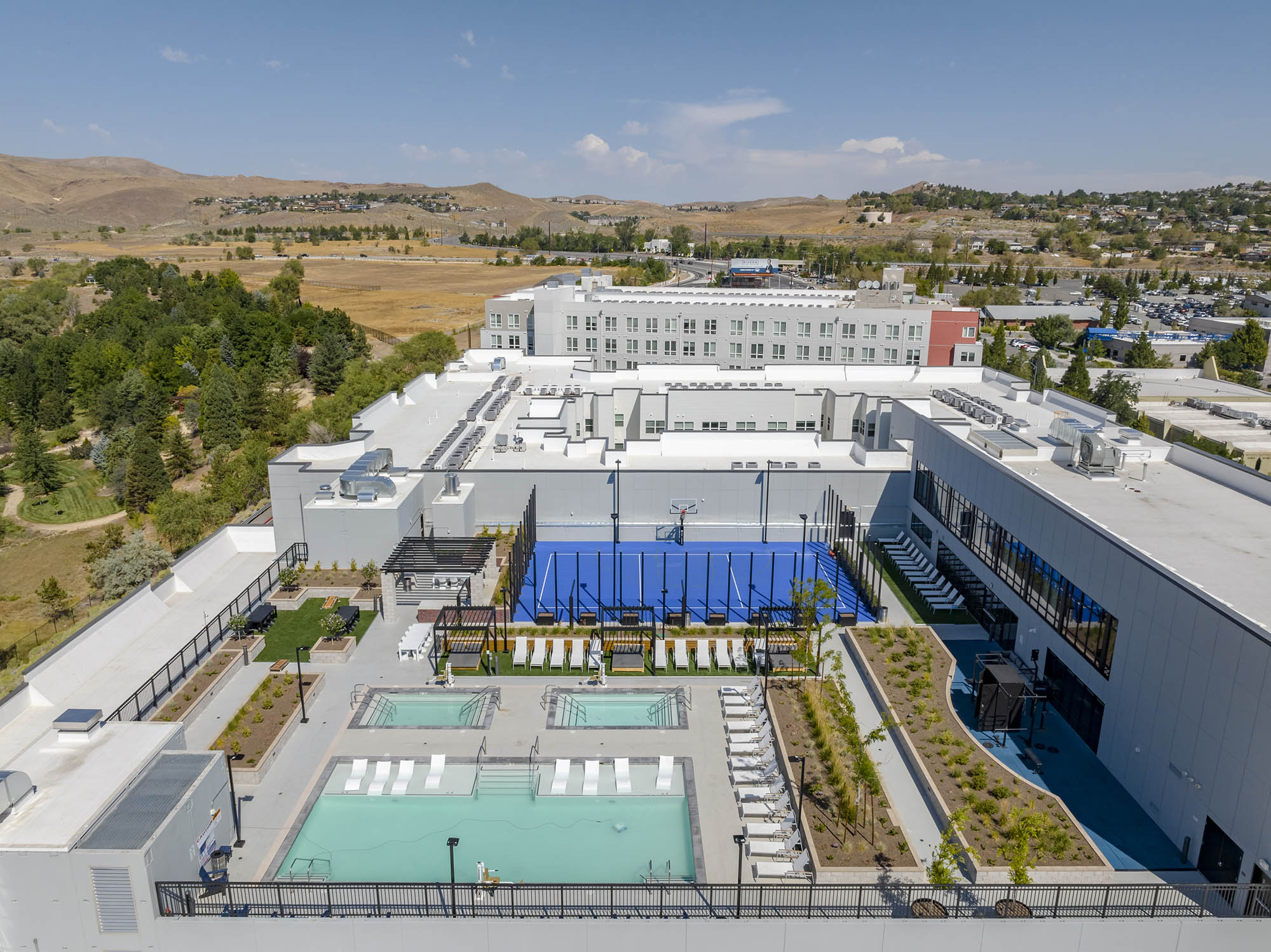 Aerial view of a modern building with pools and sports courts