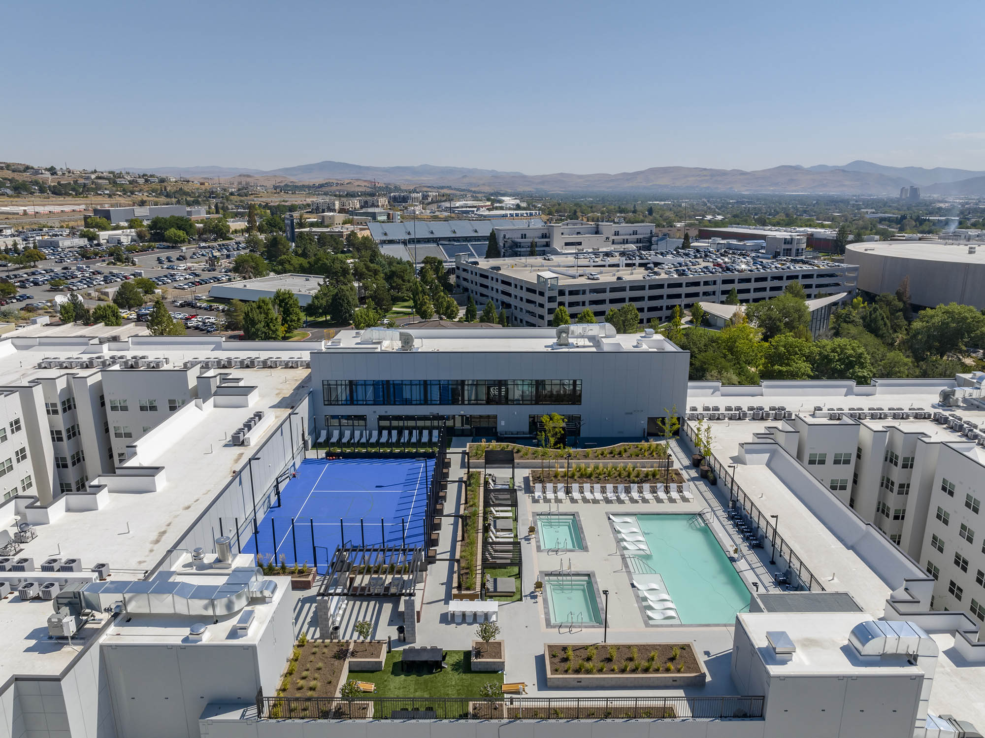 Aerial view of a modern building with pools and tennis court