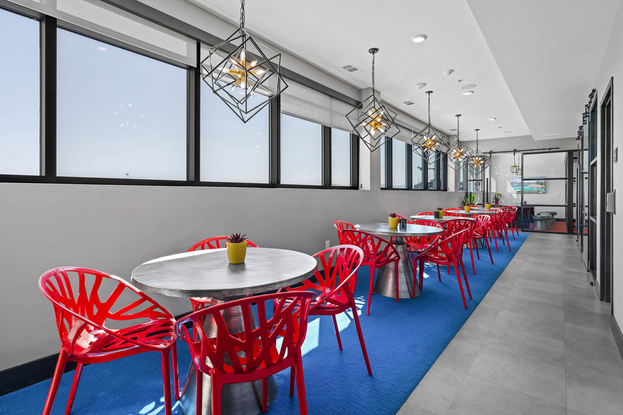 Modern dining area with red chairs round tables and large windows