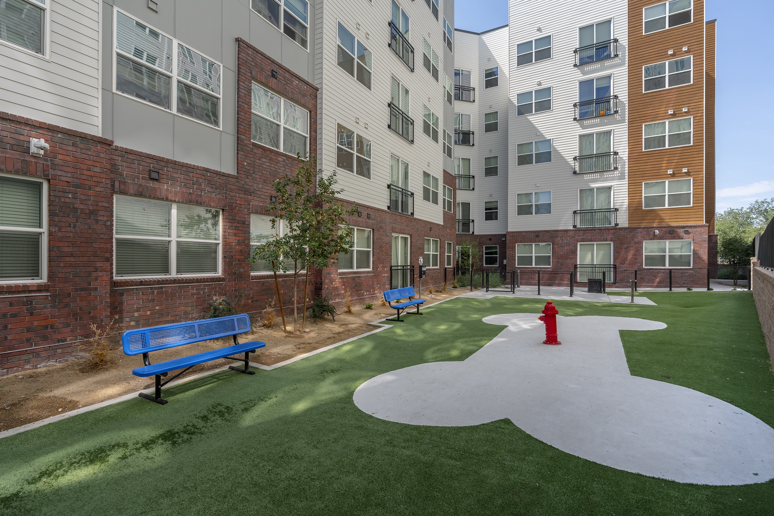 a small courtyard with green turf blue benches a